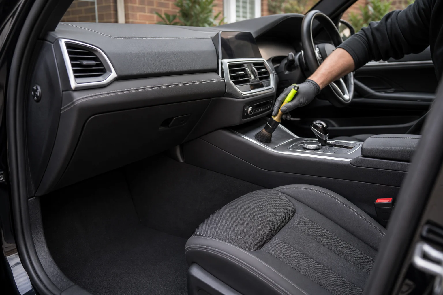 Clean dark car interior being carefully brushed